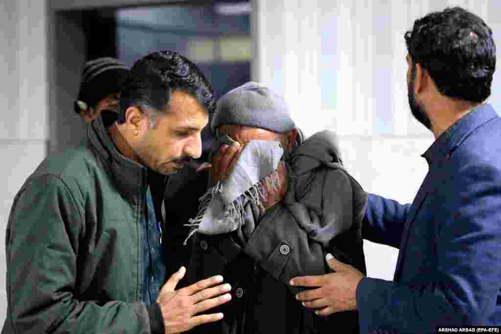 Several men comfort a relative of a victim... 