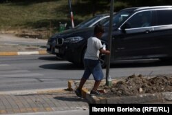 Maloletni dečak moli za novac u zamenu za čišćenje prozora na automobilima u Prištini na Kosovu.
