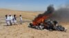 Taliban members watch the blaze after setting fire to musical instruments on the outskirts of Herat, Afghanistan, in July 2023.