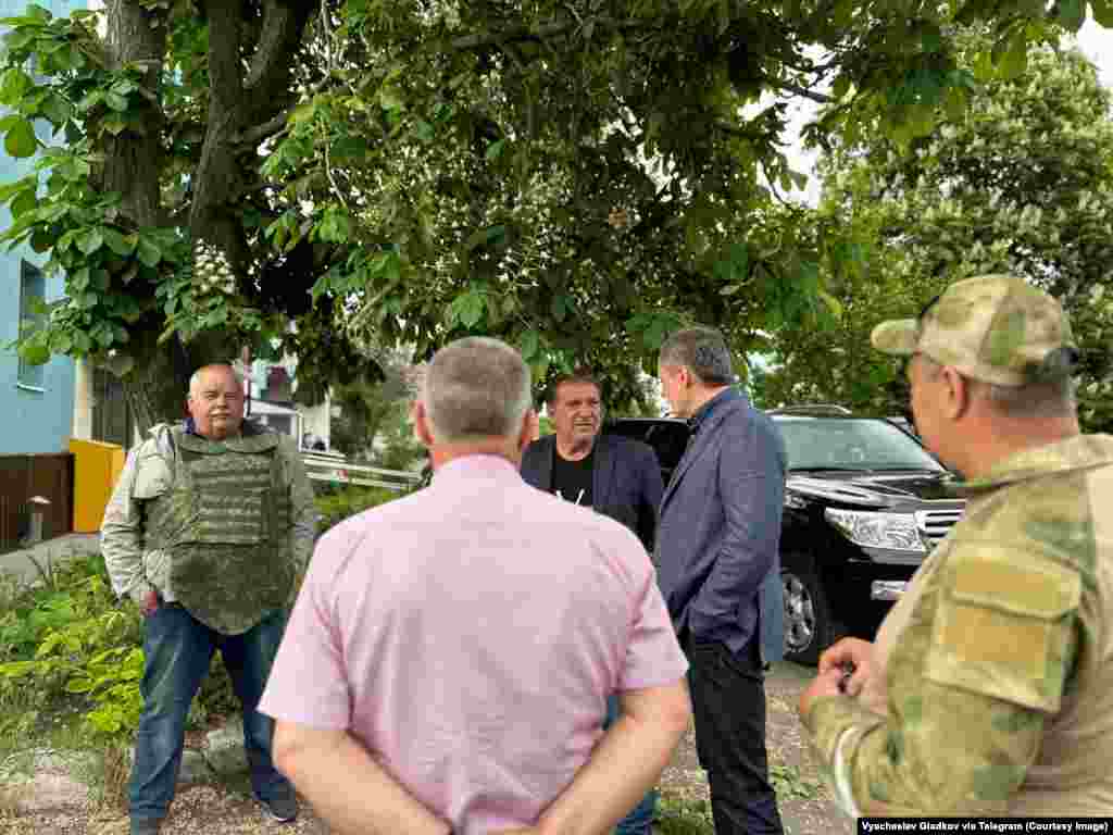 A man wears an armored vest as Belgorod Governor Vyacheslav Gladkov (in blue jacket) meets residents near where fighting took place.  Leaders of the anti-Kremlin Russian militants say cross-border raids are intended to inspire Russians to rise up against their government.
