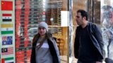 People walk past a currency exchange shop in Tehran. UN snapback sanctions are expected to hit the Iranian economy, including the value of the country's currency, the rial. 