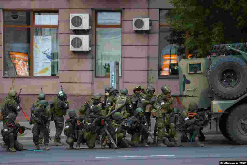 Armed men gather behind a vehicle. At bottom left of the image, a crowbar can be seen. 