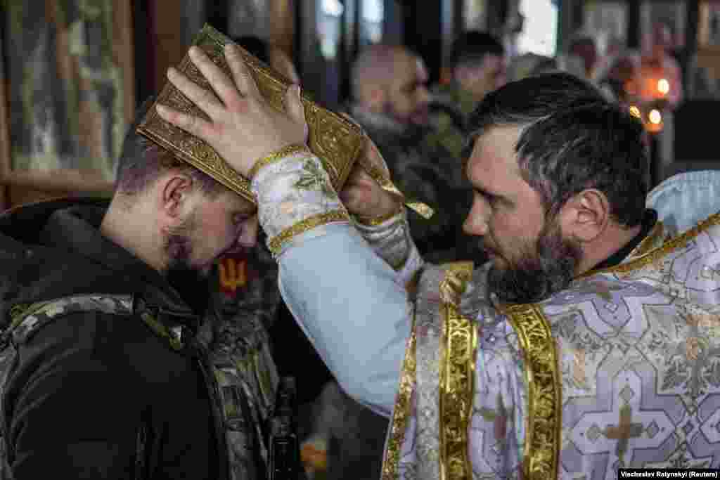 Ukrainian soldiers receive a blessing during Christmas Eve mass on December 24 near the city of Kupyansk in the Kharkiv region. Kyiv is defying Moscow as it celebrates Christmas for the first time on December 25 instead of on January 7, the day observed by the Russian Orthodox Church. 