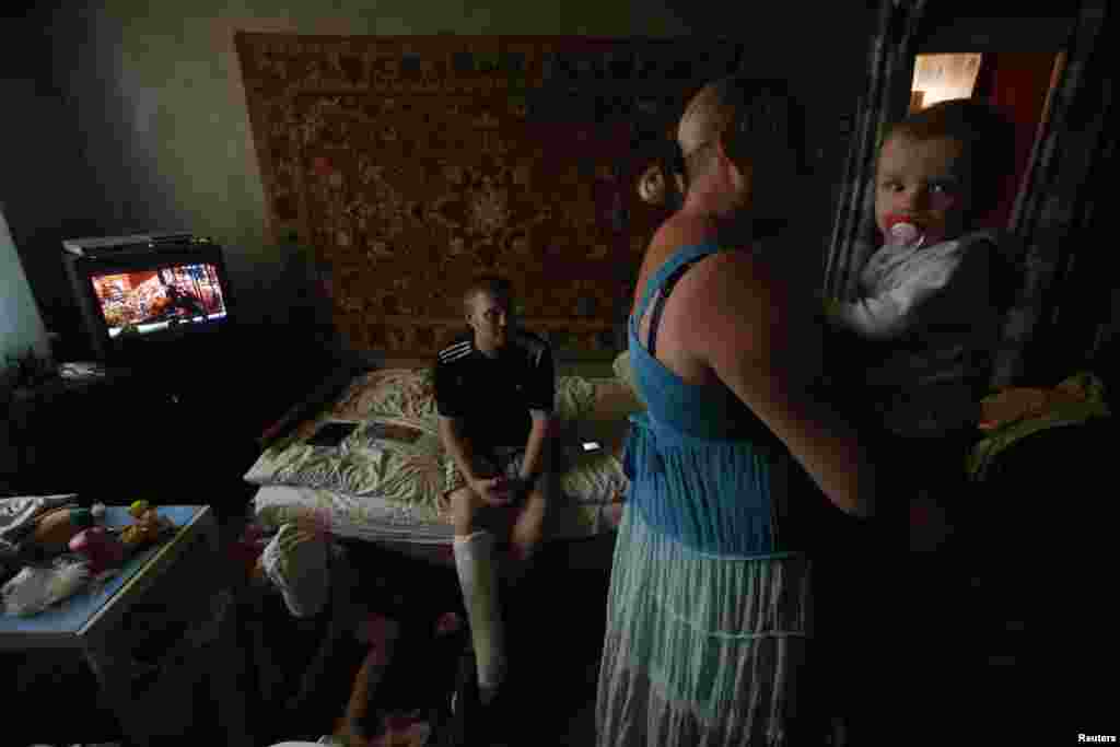 Anya Savchenko (right), Sergei Smirnov,  and their 9-month-old baby, who have fled fighting in Slovyansk, stand in their temporary accomodation in the town of Nyzhnya Krynka.