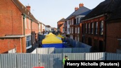 A British police officer on July 5 stands in front of screening erected in Amesbury, Britain, as forensic tents are erected after officials said it was confirmed that two people were poisoned with the nerve agent Novichok.