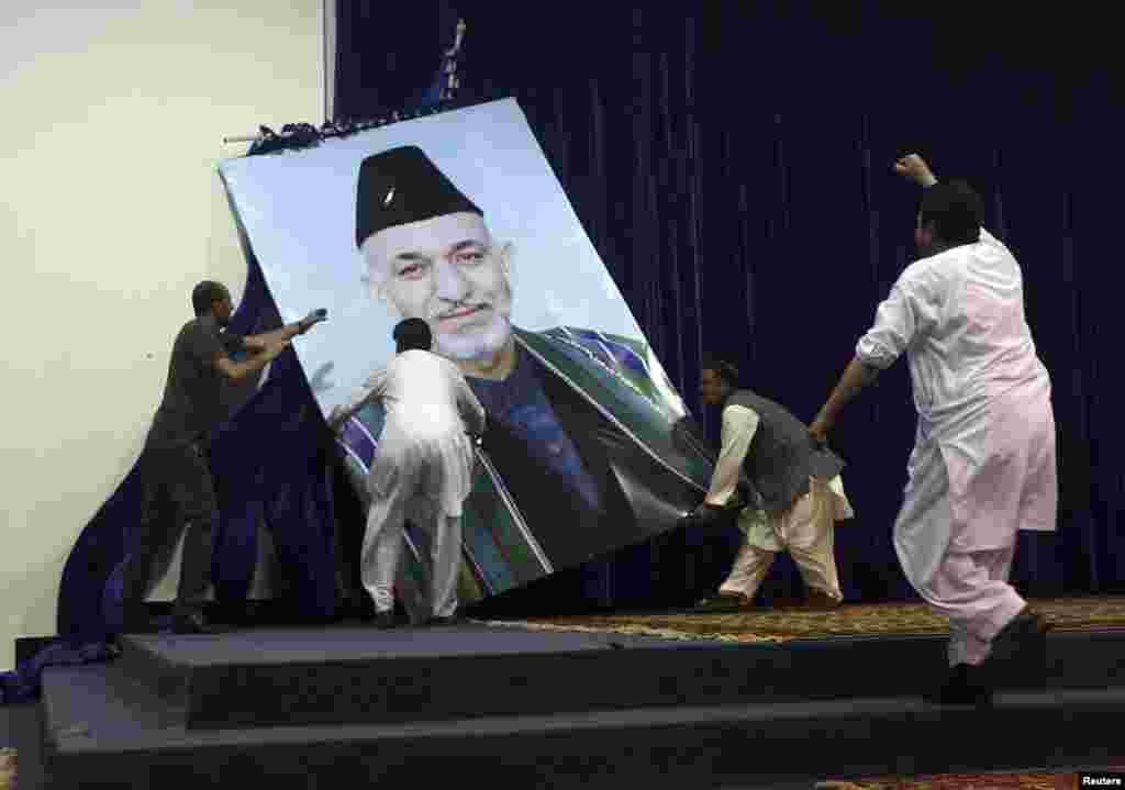Angry supporters of Afghan presidential candidate Abdullah Abdullah tear down a large portrait of Karzai before a rally in Kabul on July 8, 2014. Abdullah claimed vote fraud in the June runoff election against Ashraf Ghani. Abdullah's supporters accused Karzai of rigging the runoff in Ghani's favor.