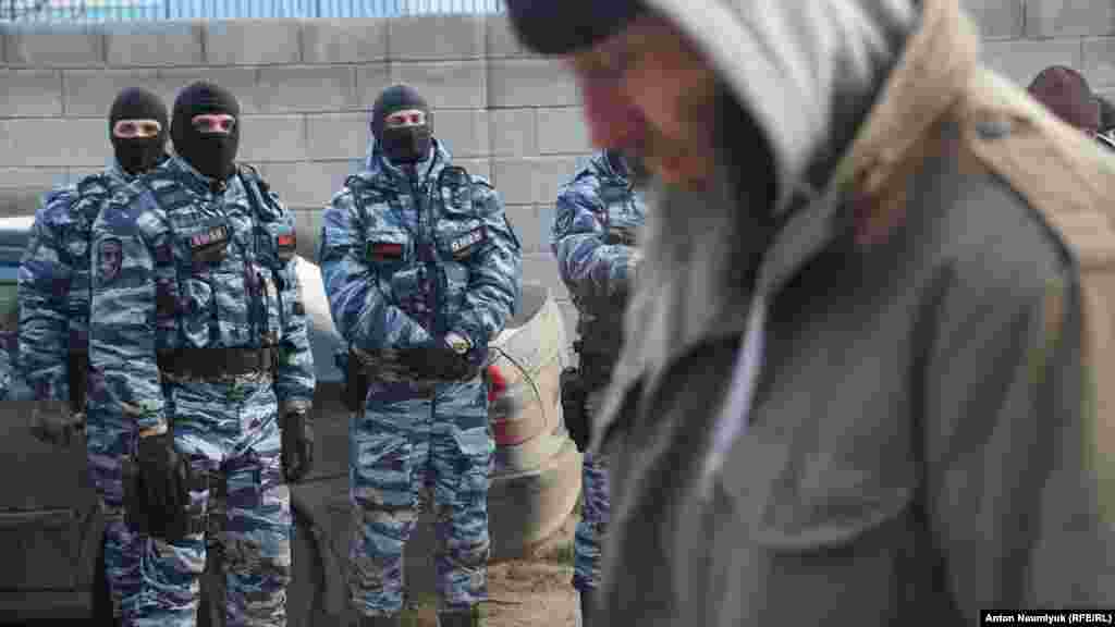 Мусульманин проходить повз російських силовиків, які заблокували збори кримськотатарської правозахисної організації  «Кримська солідарність», що обстоює права майже двох сотень кримчан, переважно кримських татар і мусульман, яких правозахисники вважають політв'язнями. Судак, 28 січня 2018 року, фото Антона Наумлюка