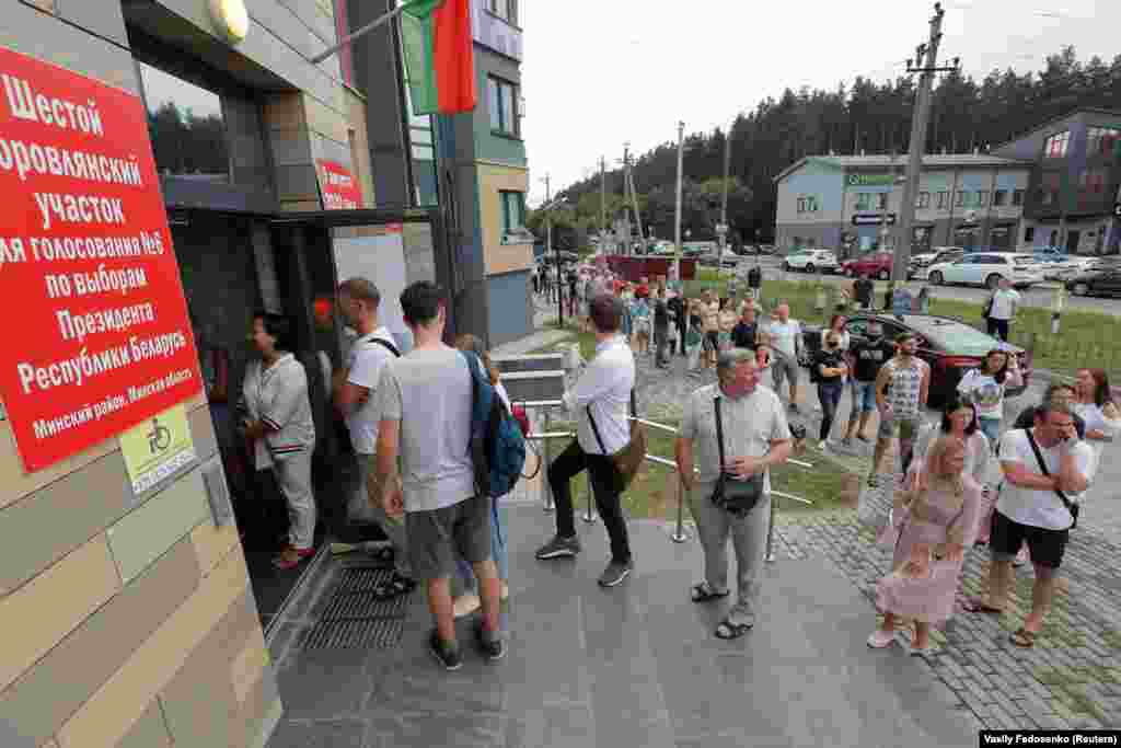 People stand in line outside a polling station in Borovlyany to cast their votes.