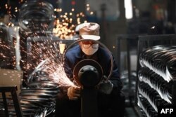 Рабочий полирует стальные обода для велосипедных колес на заводе по производству велосипедов на экспорт в городе Ханчжоу. Провинция Чжэцзян на востоке Китая