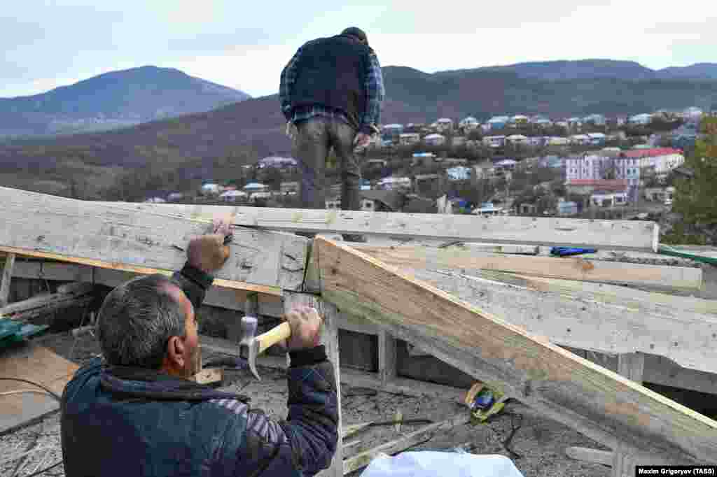Residents repair a house damaged by shelling. Dozens of civilians on both sides of the conflict were killed during the hostilities, many in missile attacks. 