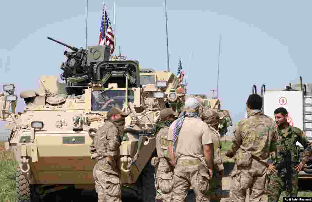 Kurdish fighters from the People's Protection Units (YPG) chat with members of U.S. forces in the Syrian town of Al-Darbasiyah in April 2017. The stated U.S. mission in Syria includes training and advising rebel forces fighting Islamic State (IS) militants. 
