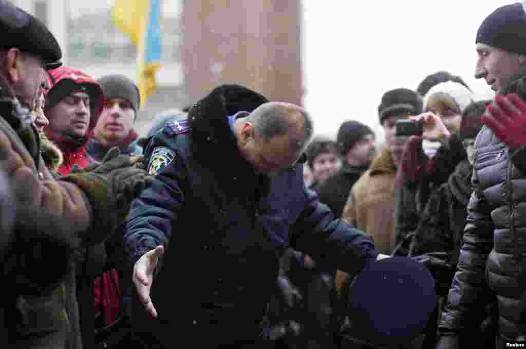 In the town of Ivano-Frankivsk, a police officer bows his head as he leaves the regional administration headquarters, which protesters attempted to take over.