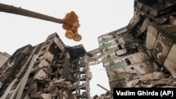 Плюшевый мишка висит на ветке поврежденного дерева возле жилого дома, разрушенного во время масштабном вторжении России в Украину. Поселок Бородянка Киевской области, 5 апреля 2022 года