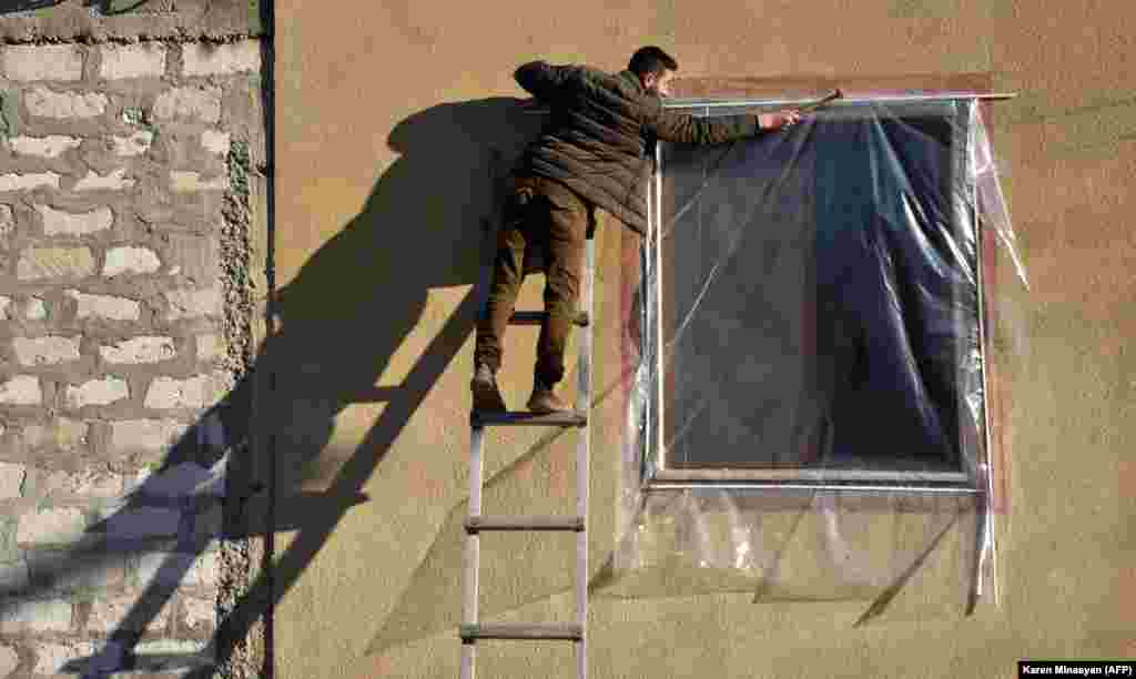 A resident repairs the shattered window of his apartment on November 24. 