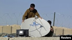 کندهار کې یو کس د کور پر بام ډېش انتن لګوي - پخوانی انځور.