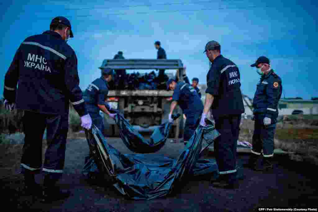 Third Prize, Spot News: Emergency workers carry the bodies of passengers on Flight MH17, which crashed near the village of Grabovo in eastern Ukraine. (Petr Shelomovskiy)