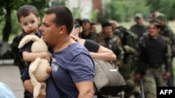 A man carries his son as he leaves his apartment building during an ongoing shoot-out between pro-Russian militants and border guards defending the Federal Border Headquarters in Luhansk on June 2.