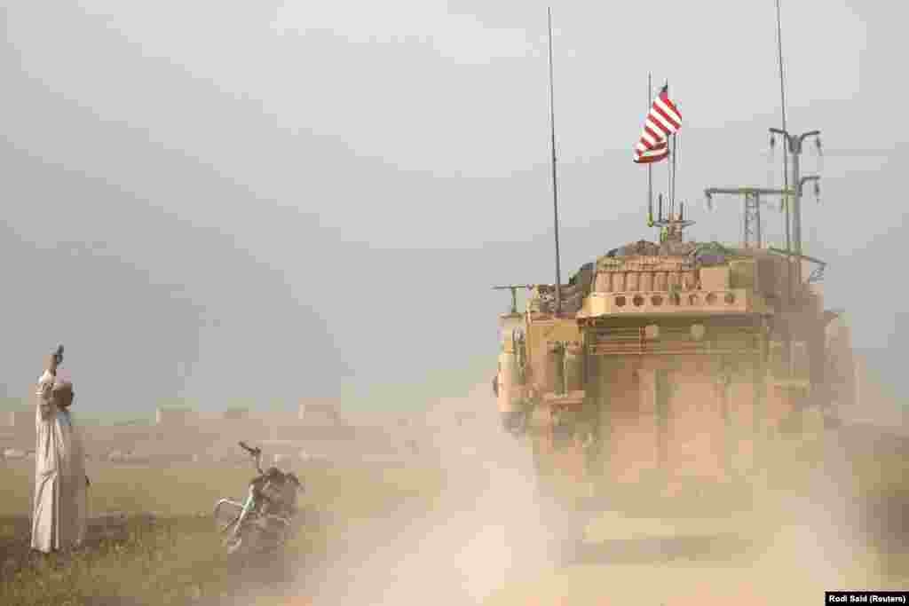 A local flashes a "V for victory" sign at U.S. military vehicles near Al-Darbasiyah. According to the U.S. Defense Department, the coalition has recaptured around 90 percent of the territory once held by IS in Syria. 
