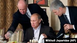 Businessman Yevgeny Prigozhin (left) serves food to then-Russian Prime Minister Vladimir Putin in 2011.
